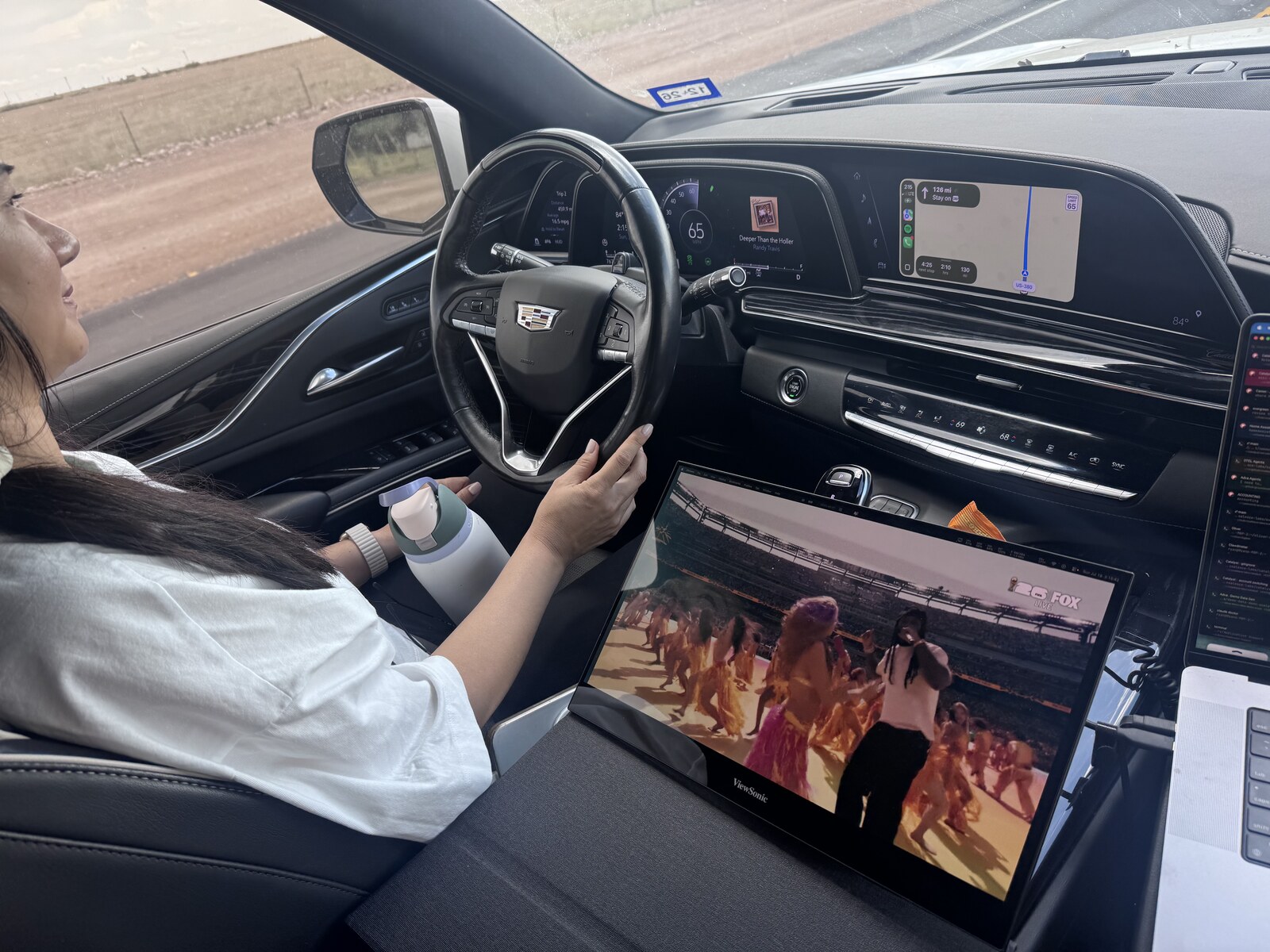 Molly driving the Escalade on the highway with the dashboard and laptop visible