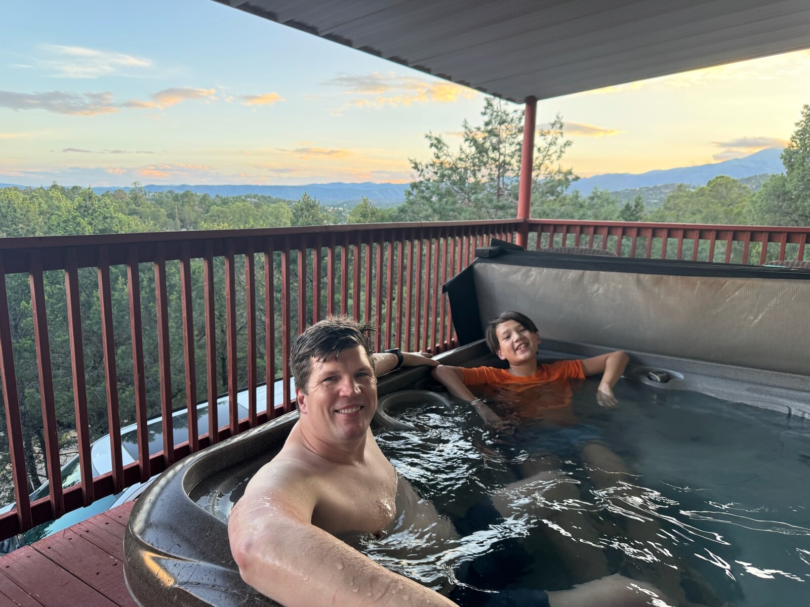 Ryan and Owen in the hot tub with mountain views behind them